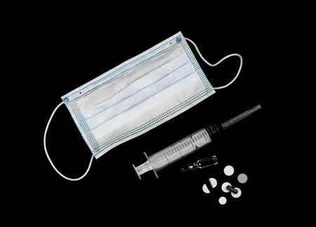 Medical mask, syringe, ampoule and tablets. The view from the top. Isolated on a black background.の写真素材
