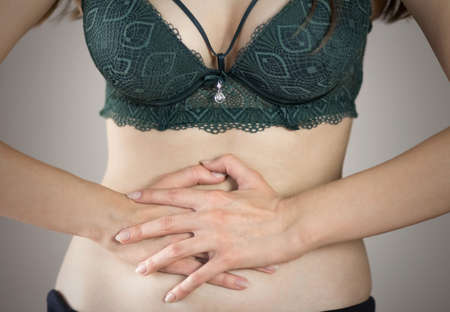 Abdominal pain in a woman. Highlighted in red. On a gray background. Close up.