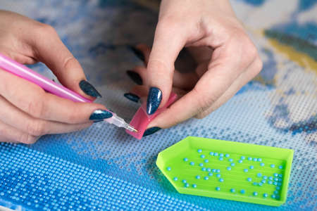 Collecting diamond embroidery, diamond mosaic. Colored crystals. Tools. Close up.