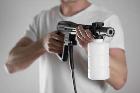 A man holds a high pressure washer. Close-up. Isolated on a gray background.の写真素材