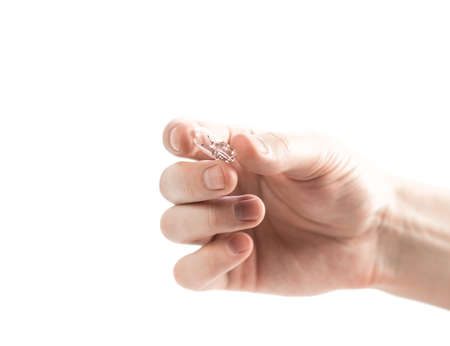 The hand holds a small glass light bulb. Close up. Isolated on a white background.