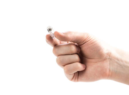 The hand holds a small burnt-out light bulb. Close up. Isolated on a white background.