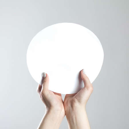 Hands hold a round blank sheet of paper. A clean flyer in your hands. For your text. Isolated on a...