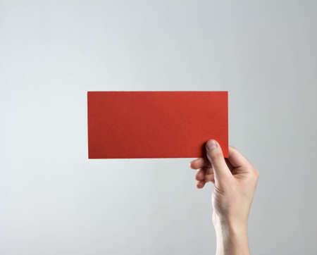 The hand holds a red flyer. A clean flyer in your hands. For your text. Isolated on a gray background.の写真素材