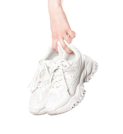 Hand holding a light leather womens sneakers. Close up. Isolated on a white background.の写真素材