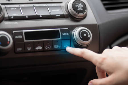 The hand adjusts the air conditioner in the car. Close up.