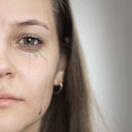A girl with leaking mascara from tears. The girl is crying. close up. isolated.の写真素材