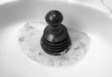 Cleaning a white ceramic sink with a black plunger. closeup.の写真素材