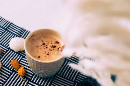 Cup of coffee next to shells, a navy blue cloth and white dried flowers. marine concept. Vacation preparation. Holiday souvenir.の写真素材
