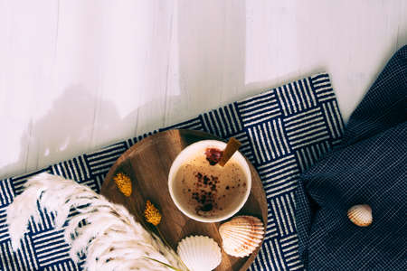 Cup of coffee next to shells, a navy blue cloth and white dried flowers. marine concept. Vacation preparation. Holiday souvenir.の写真素材