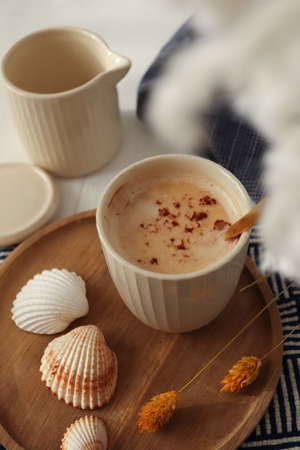 Cup of coffee next to shells, a navy blue cloth and white dried flowers. marine concept. Vacation preparation. Holiday souvenir.の写真素材