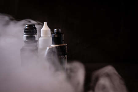 Vapers and liquid to vape between vapor on black background.の写真素材
