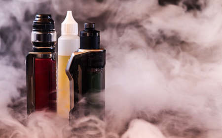 Vapers and liquid to vape between vapor on black background.の写真素材