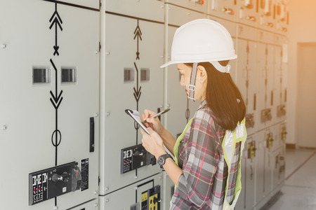 women engineer working on checking and maintenance electrical equipment ;women engineer checking status switchgear with checklistの写真素材