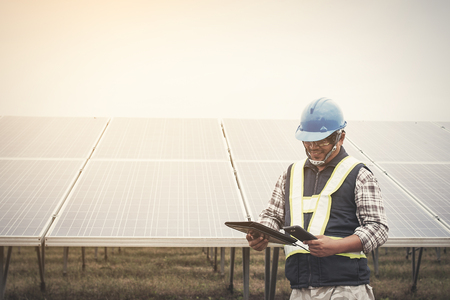 engineer charging his phone with small solar cell at solar power plantの写真素材