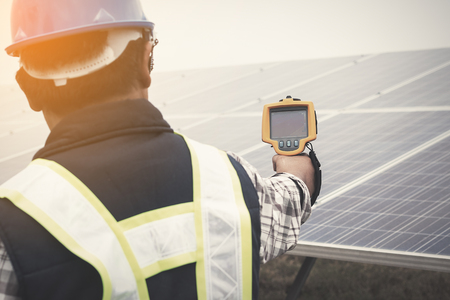 engineer or electrician working on  maintenance equipment at industry solar power;  engineer using thermal imager to check temperature heat of solar panelの写真素材
