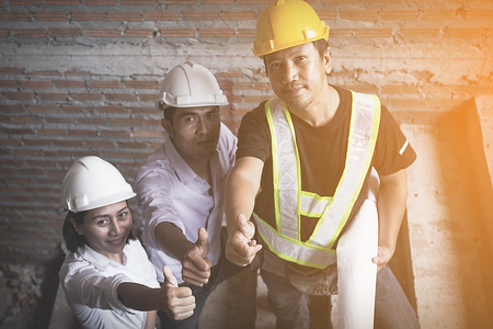 engineer working on checking progress of construction with blueprint at construction site ; engineering team working on process and thumbs up for progress of construction projectの写真素材