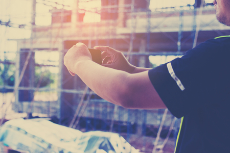 engineer working on checking progress of construction with smart phone at construction siteの写真素材