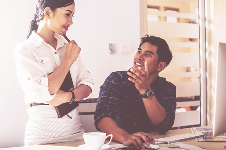 Two young business people analyze the results and discuss them at morning at modern officeの写真素材