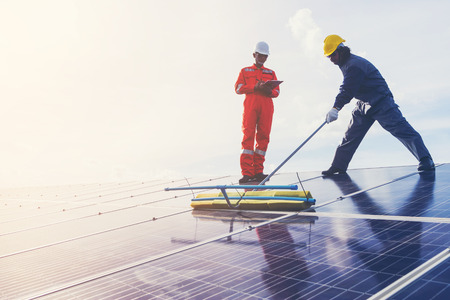 technician operating and cleaning solar panels at generating power of solar power plant; technician in industry uniform on level of job description at industrialの写真素材