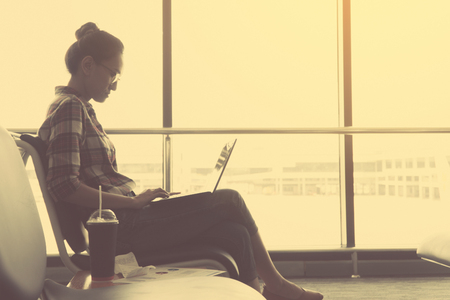 young female using laptop and business chart while while waiting for her flight at airport terminal ;business travellers waiting for their flight at airport
の写真素材