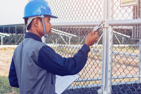 engineer or electrician working on checking and maintenance equipment at green energy solar power plant; checking status step up transformer high voltage at transformer yardの写真素材