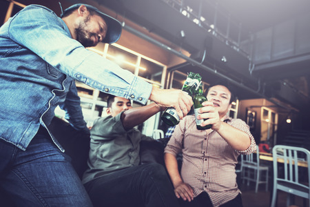 businessteam relaxing and talking in nightclub ; businessman drinking beverage in counter at nightclubの写真素材