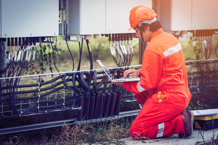 engineer or electrician holding laptop for inspect and checking string inverter by wifi technology ;smart technology for operate solar power plantの写真素材