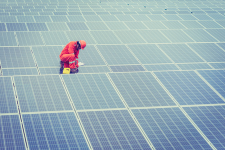 engineer in solar power plant working on installing solar panel ; operation of solar power plant by smart operatorの写真素材