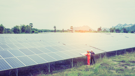 engineer in solar power plant working on installing solar panel ; smart operator holding blueprint for installing equipment in solar power plantの写真素材