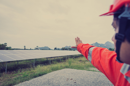 engineer in solar power plant working on installing solar panel ; smart operator holding blueprint for installing equipment in solar power plantの写真素材