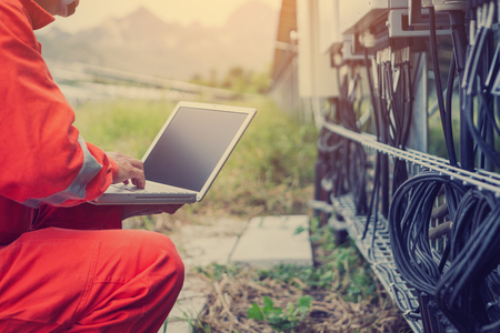 engineer or electrician holding laptop for inspect and checking string inverter by wifi technology ;smart technology for operate solar power plantの写真素材