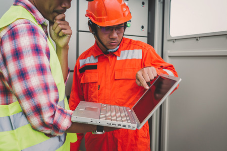 engineer or electrician holding laptop for inspect and checking main distribution board by wifi...