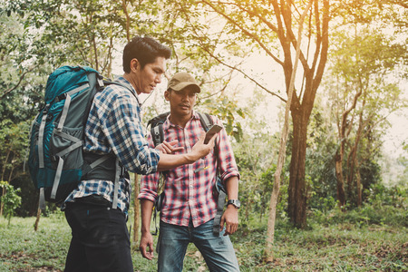 Hiking man with backpack using phone in mountains, Travel lifestyle success concept adventureの写真素材