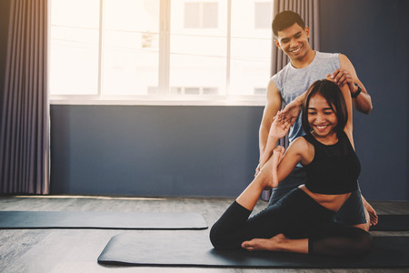 Yoga group concept; young man teaching woman practicing yoga in class; feeling Calmness and relax in yoga classの写真素材