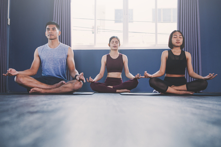 Yoga group concept; young people practicing yoga in class; feeling Calmness and relax in yoga classの写真素材