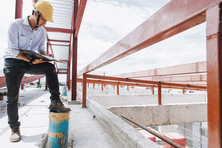 Project engineer, engineer working on blueprint architectural project at construction siteの写真素材
