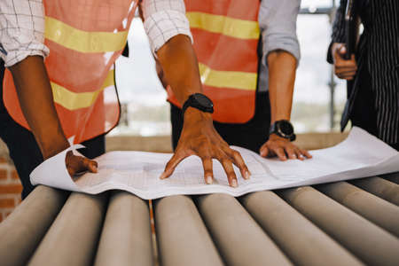 Project engineer, engineer working on blueprint architectural project at construction siteの写真素材