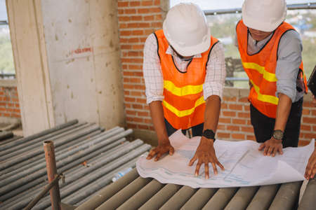 Project engineer, engineer working on blueprint architectural project at construction site