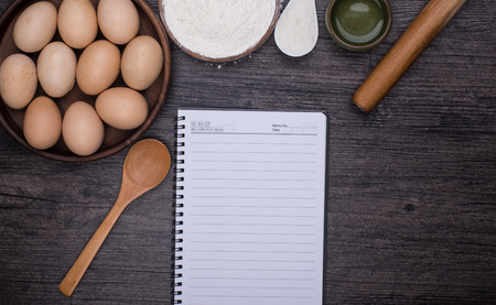 Wooden background with baking ingredients (eggs, flour and rolling pin) over rustic texture. Top view. Space for text. Food or cooking concept.の写真素材