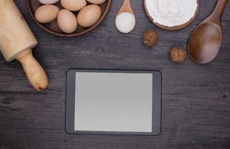 Wooden background with baking ingredients (eggs, flour and rolling pin) over rustic texture. Top view. Space for text. Food or cooking concept.の写真素材