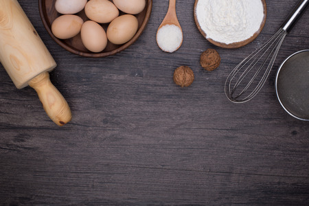 Wooden background with baking ingredients (eggs, flour and rolling pin) over rustic texture. Top view. Space for text. Food or cooking concept.の写真素材