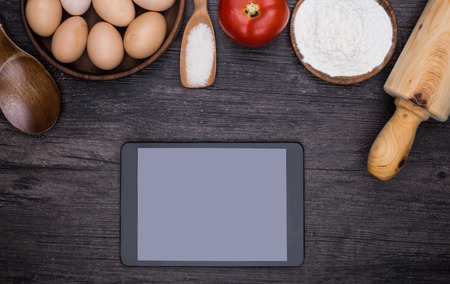 Wooden background with baking ingredients (eggs, flour and rolling pin) over rustic texture. Top view. Space for text. Food or cooking concept.の写真素材
