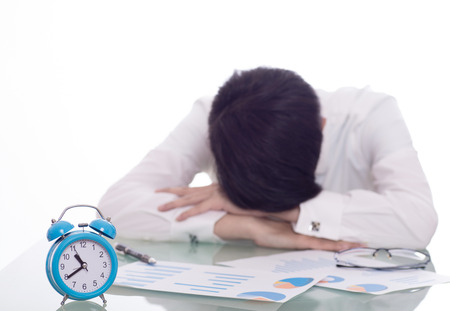 young crazy businessman punching switching off alarm clock sitting at office desk working with computer laptop in deadline project concept and business stress conceptの写真素材