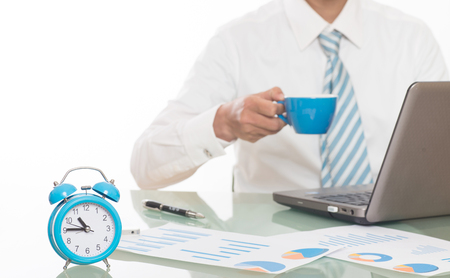 young crazy businessman punching switching off alarm clock sitting at office desk working with computer laptop in deadline project concept and business stress conceptの写真素材