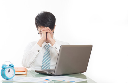 young crazy businessman punching switching off alarm clock sitting at office desk working with computer laptop in deadline project concept and business stress conceptの写真素材