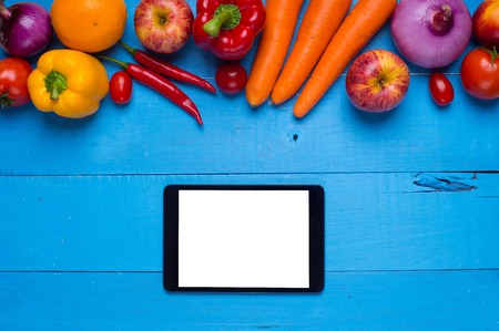 studio photography of different fruits and vegetables with tablet on old wooden tableの写真素材
