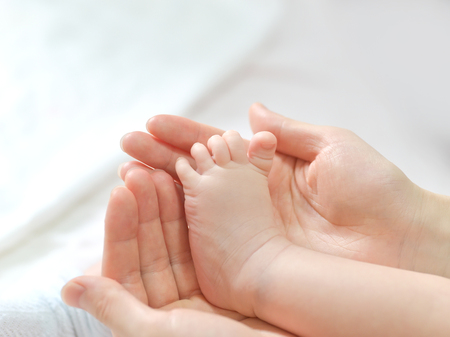 Baby feet in mother hands. Mom and her Child. Happy Family concept. Beautiful conceptual image of Maternityの写真素材
