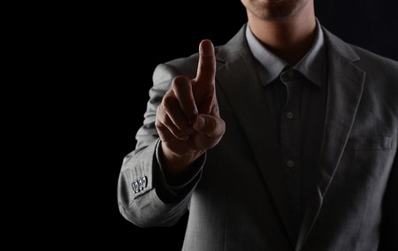 Men in suits in studios, looking forward with their fingers against a black backgroundの写真素材