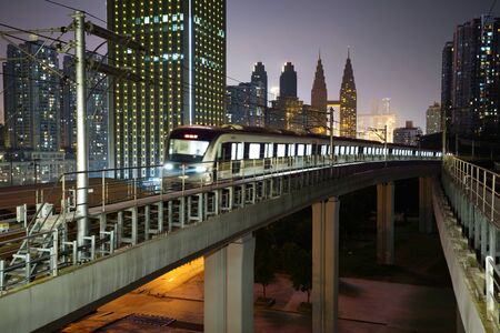 At night, the light rail train shuttles through the city.の写真素材